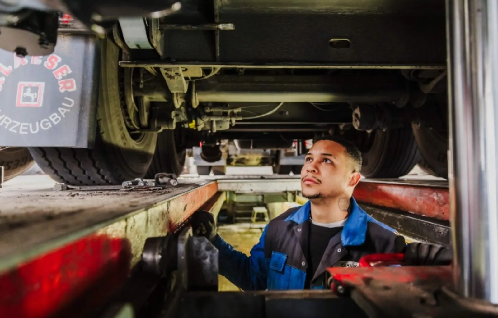 Mechaniker prüft die Technik unter dem Fahrgestell eines Nutzfahrzeugs