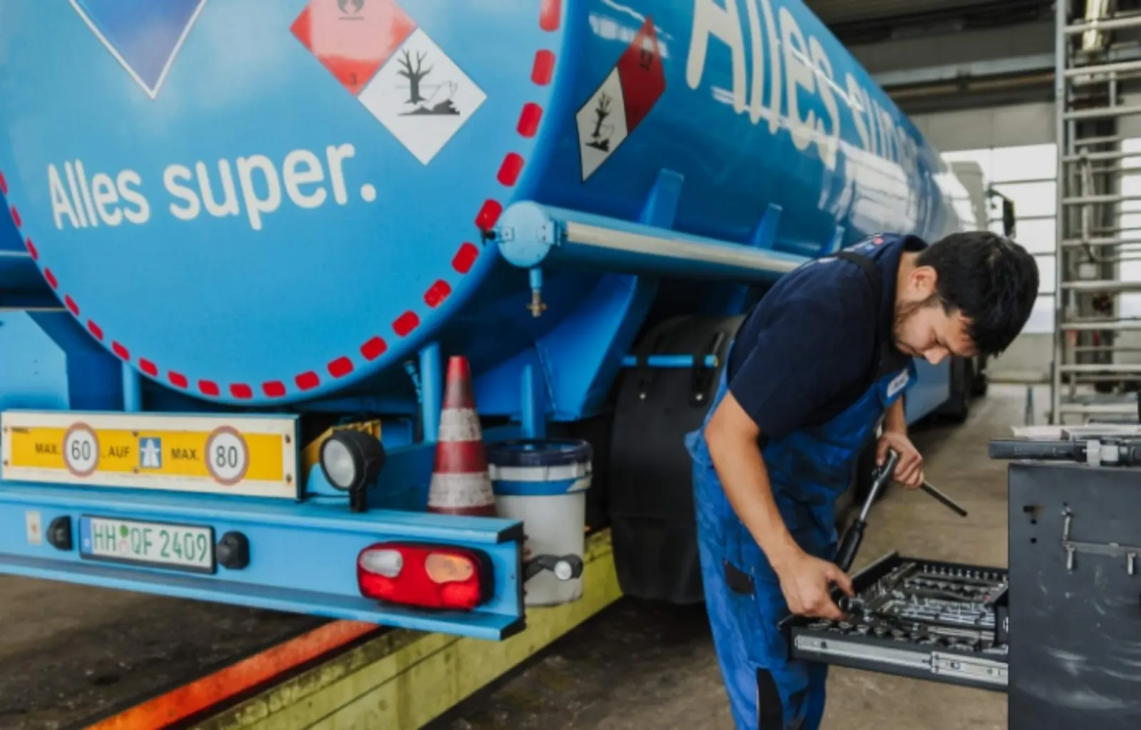 Techniker der NWR GmbH arbeitet am Heck eines blauen Tankaufliegers