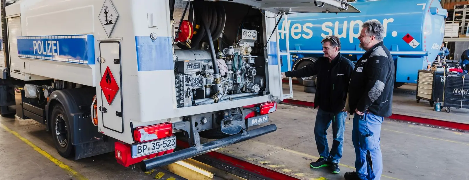 Zwei Mitarbeiter der NWR GmbH prüfen die Technik eines Tankfahrzeugs